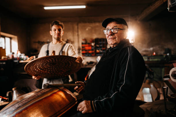 An old man,a worker in a workshop for making cauldrons for an alcohol distillation