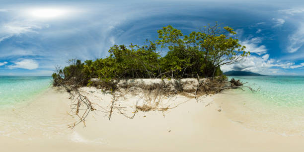 Beach with white sand and clear ocean water and waves. Mantigue Island. Blue sky and clouds. Camiguin, Philippines. VR 360.