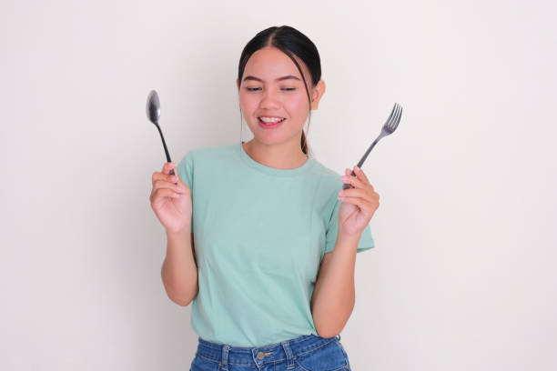 istock A woman staring at something with happy face while holding spoon and fork 2190880828