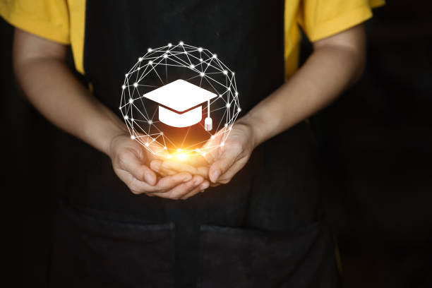 istock A person is holding a black apron with a white graduation cap on it 2190881935