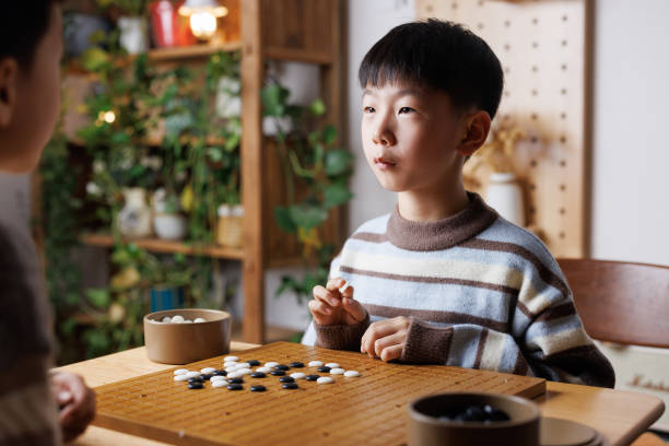 istock brothers are learning Go - Board Game at home 2190883787