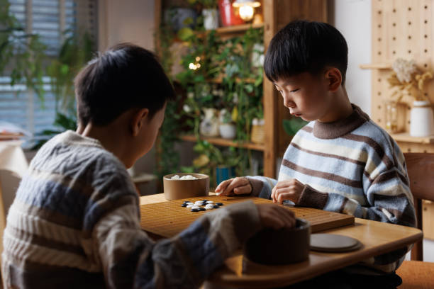 istock two brothers are learning Go - Board Game at home 2190883791