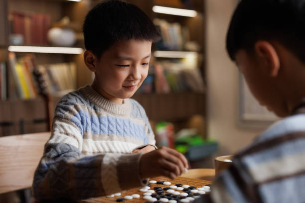 istock cute brothers are learning Go - Board Game at home 2190883801