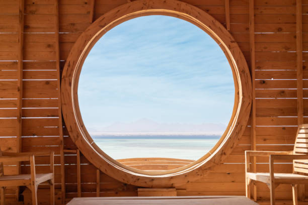 istock Tranquil indoor space with large circular window overlooking serene sea and distant mountains 2190884960