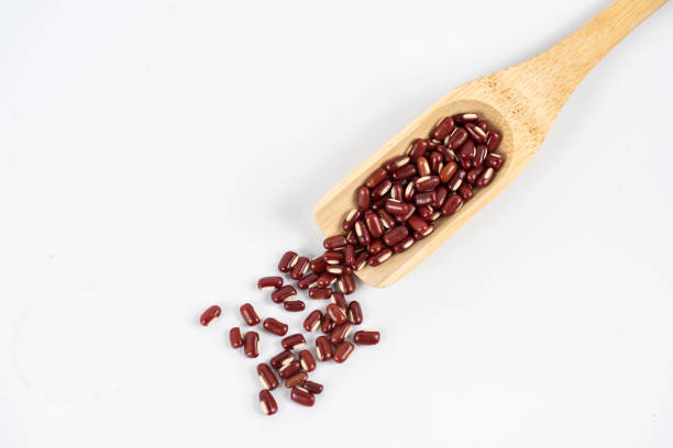 Red beans in wooden spoon on white background