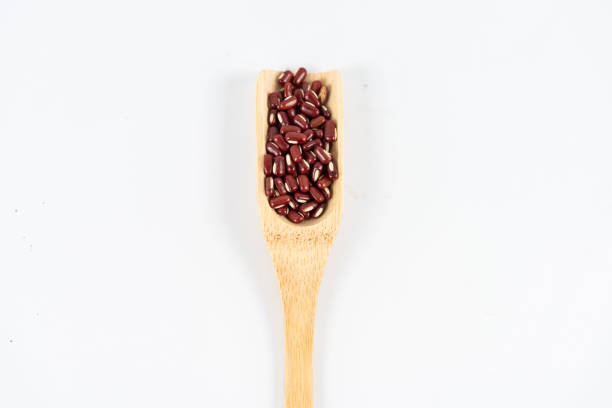 Red beans in wooden spoon on white background