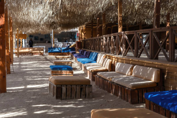 istock Tranquil beachside lounge with wooden seating and dappled sunlight 2190885124