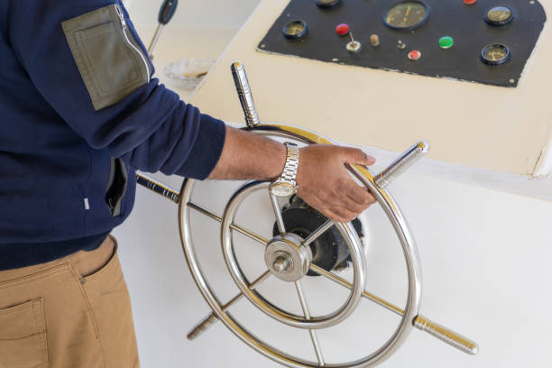 A detailed close-up of a person steering a boat using a stainless steel wheel, set against the backdrop of a control panel with colorful buttons. the scene essence of maritime adventure and the hands-on experience of navigating at sea. perfect for use in themes of travel, exploration, and nautical technology. vibrant colors and clear details highlight the precision and craftsmanship of marine equipment. ideal for showcasing the art of seafaring and the allure of ocean journeys.