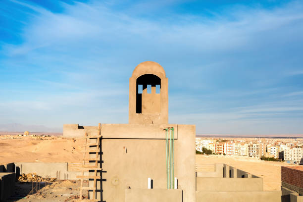 Captivating image of a traditional desert structure set against an urban skyline under a vast blue sky. the scene blends the arid desert with the modern city, creating a unique juxtaposition. the serene environment is perfect for themes of travel, culture, or architecture, the contrast between tradition and modernity.