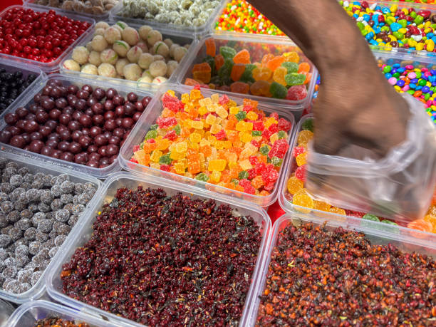 A person is reaching into a container of candy. The candy is in many different colors and shapes