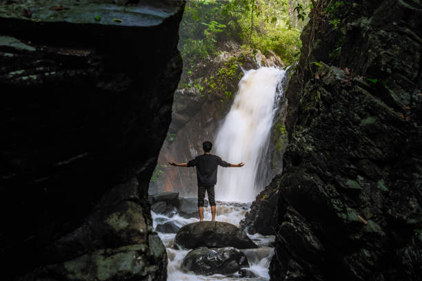 istock Man standing in front of beautiful Waterfall. Beautiful landscape with waterfall and cliff scenery 2190891930