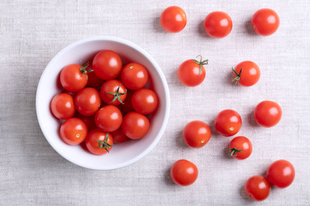 istock Small red cherry tomatoes in a white bowl on linen fabric 2190893188