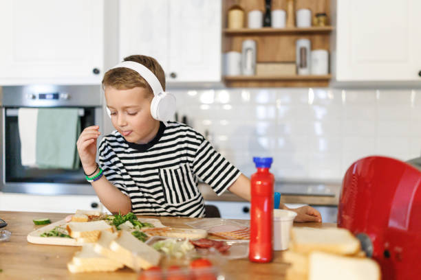 istock Boy eating sandwich he made himself in the kitchen at home 2190895158