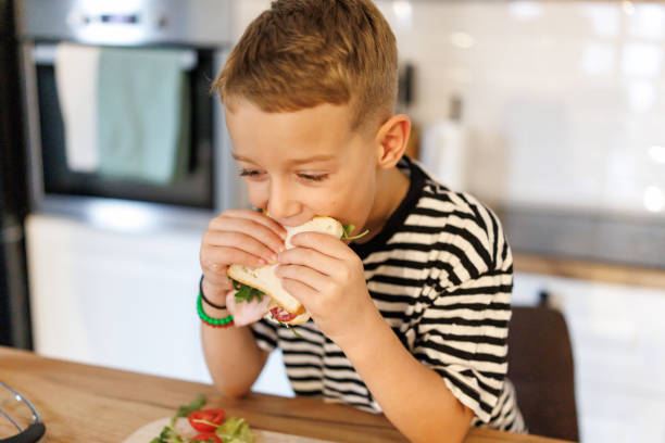 istock Boy eating sandwich in the kitchen 2190896260