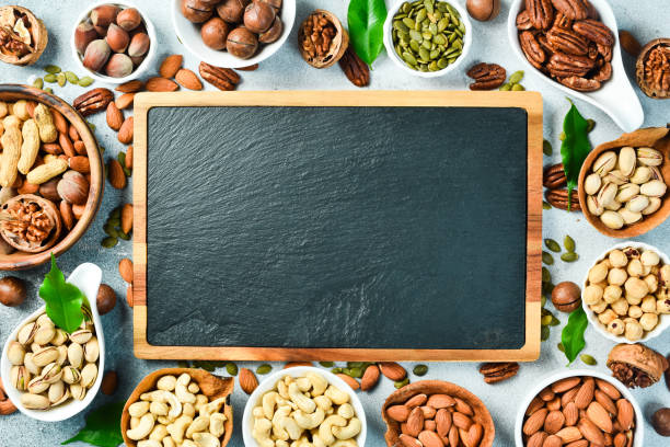 istock A slate board and a set of nuts in a bowl on a light stone background. Free space for text. Healthy snacks. Nuts 2190898616