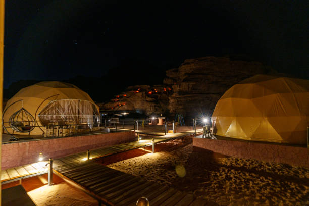 Illuminated domes under a star-lit desert sky create a serene and adventurous nighttime camping atmosphere with cozy accommodations. Illuminated domes under a star-lit desert sky create a serene and adventurous nighttime camping atmosphere with cozy accommodations. geodesic dome dome space architecture stock pictures, royalty-free photos & images