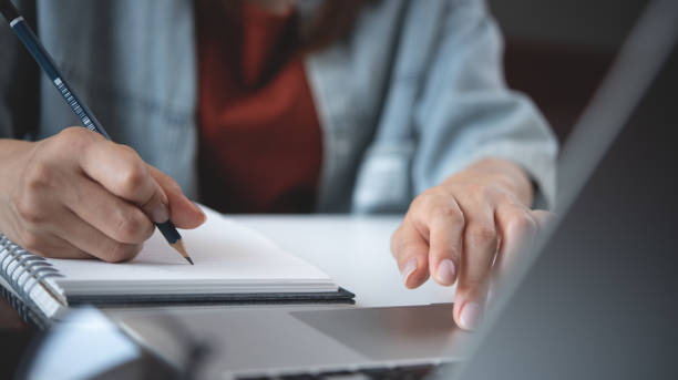 istock Woman using laptop computer searching ideas and making a note on notebook. Business woman working on laptop and planning, writing on notepad. Student studying online class, e-learning 2190901660