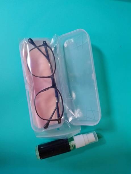 istock A pair of black-framed glasses, a cleaning cloth, and a cleaning solution are neatly arranged on a blue surface. 2190904776