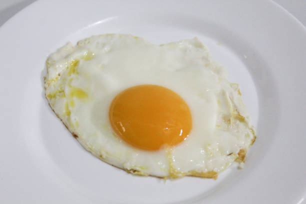 istock Fried egg or sunny side up, on a white plate. Round orange egg yolk in the middle. Isolated on white background 2190905535