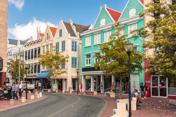 Willemstad, Curacao, Netherlands - January 6, 2018: A vibrant street scene in the historic district of Willemstad, showcasing colorful Dutch colonial architecture and bustling pedestrian activity.