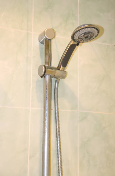 istock Shower head with hose with limescale deposits in holder on wall in bathroom 2190906937