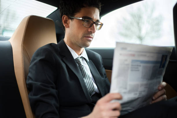 istock Businessman reading newspaper while sitting in car 2190907864
