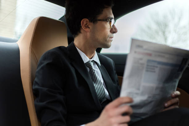 istock Businessman reading newspaper while sitting in car 2190908022