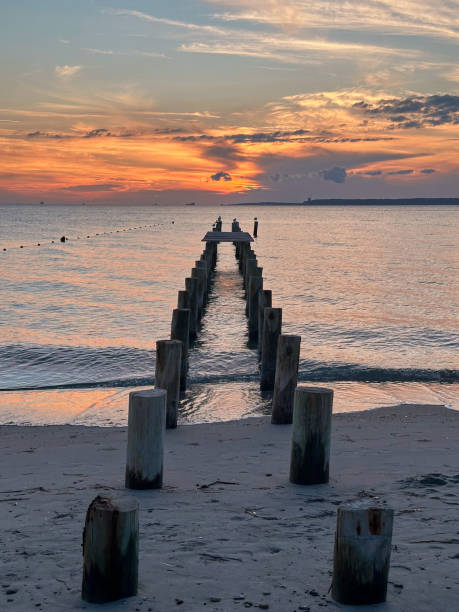 istock Wooden pier remnants at sunset on a calm beach 2190909618
