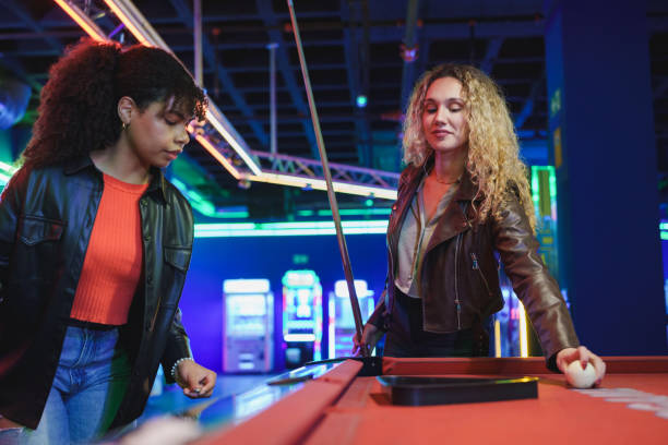 istock Two young women playing billiards in an amusement arcade 2190911509