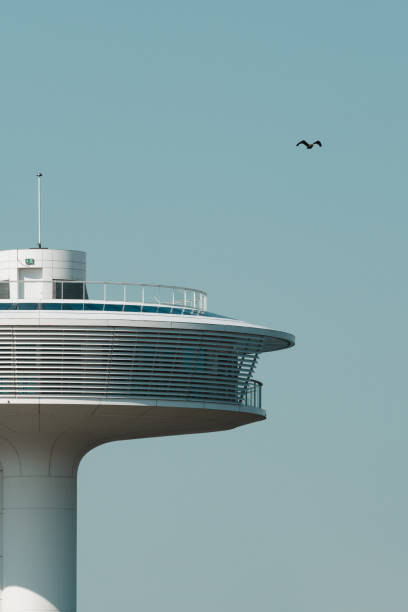 The air traffic control tower at Sydney Kingsford Smith Airport. The silhouettes of air traffic controllers are visible at work. This image was taken from near Kyeemagh Beach, Botany Bay on a cold and sunny morning at sunrise on 24 May 2025.
