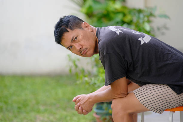 Asian guy sitting and taking a break after working in the garden