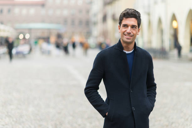 istock Young man smiling and walking in city center square 2190917401