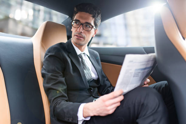 istock Businessman reading newspaper while traveling in car 2190918191