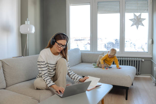 istock Woman working remotely on a laptop while child plays at home 2190925976