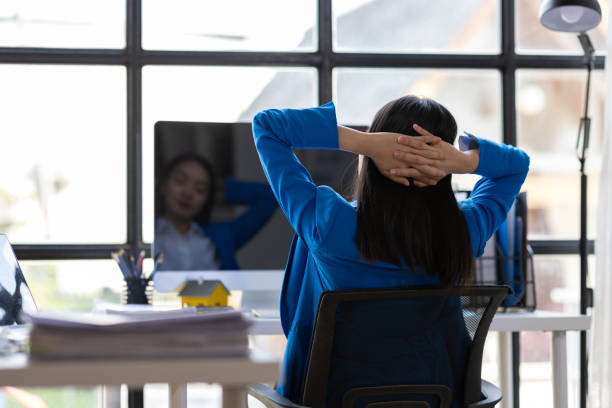 istock Businesswoman working on computer at office. She was stretching to relieve herself from sitting in an office chair for a long time. 2190943138
