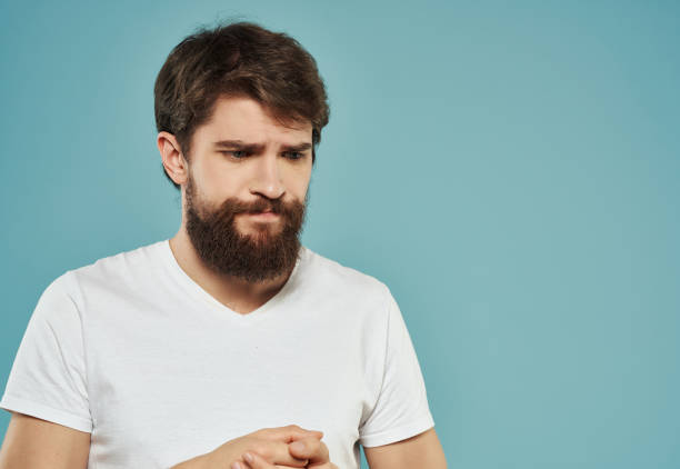 Man in a white t-shirt irritated facial expression Studio. High quality photo