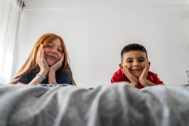 Portrait of siblings on bed at home