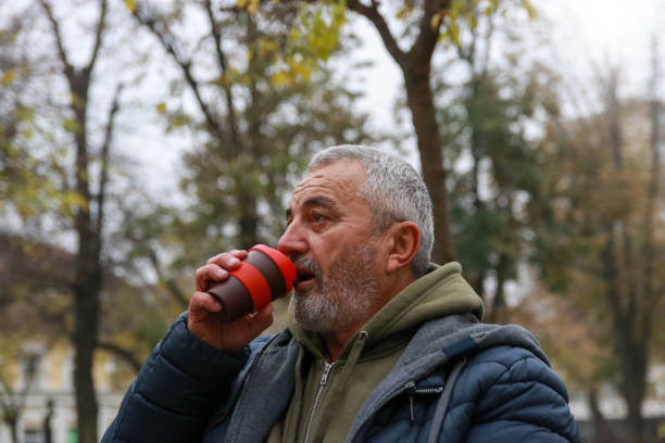 istock Senior man on autumn cold day working on laptop and drink coffee 2190954385