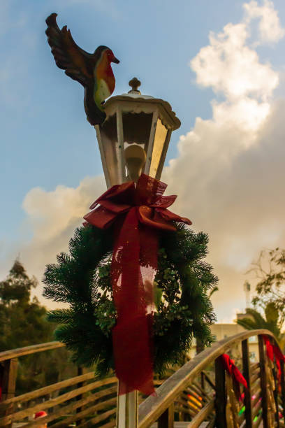 A vintage lantern adorned with a Christmas wreath, ribbon, and decorative decor against a twilight sky. Capturing festive outdoor holiday spirit for seasonal inspiration and celebration.