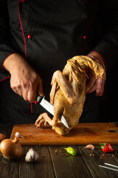 istock A chef expertly cuts into a whole duck on a wooden board surrounded by fresh vegetables and spices. The atmosphere is warm and inviting, highlighting culinary artistry 2190956676