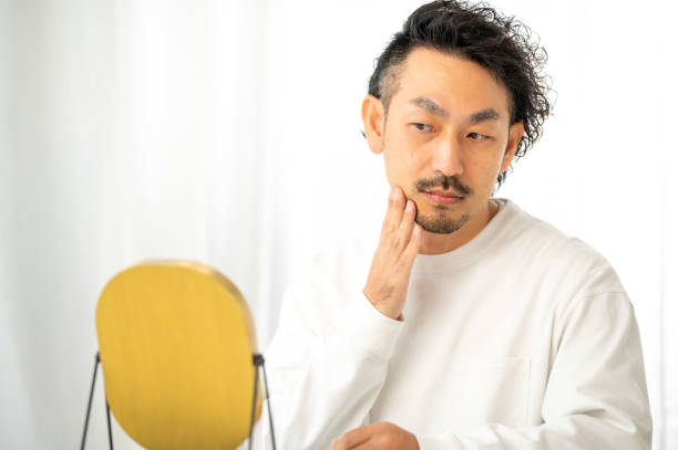 istock A Japanese man checking his skin in a mirror 2190964995