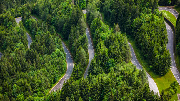 istock Aerial Drone View of Winding Road Through Dense Pine Forest 2190966009