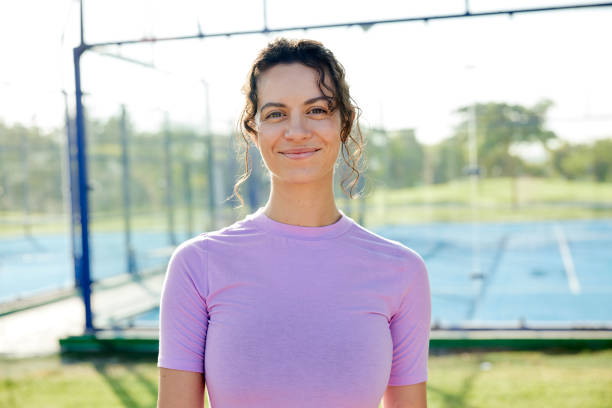 A young woman in sports clothes poses confidently for a portrait in a Dubai public park.