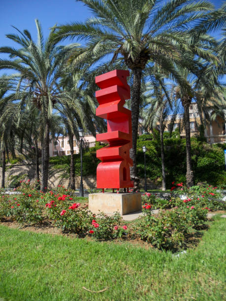 istock Vibrant red sculpture amidst palm trees and roses 2190972927
