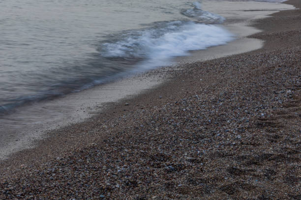 istock Sea waves crash onto a pebble beach 2190975820