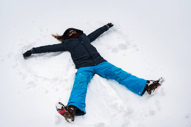 istock Young woman making snow angel in fresh snow 2190977447