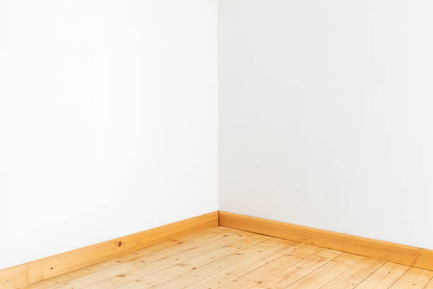 Corner and white wall with wooden floorboards and skirting board