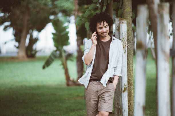 Man smiling on phone in green park