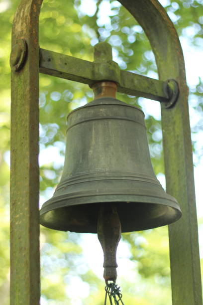 An old bell hangs gracefully in a natural setting, its weathered surface telling stories of time gone by