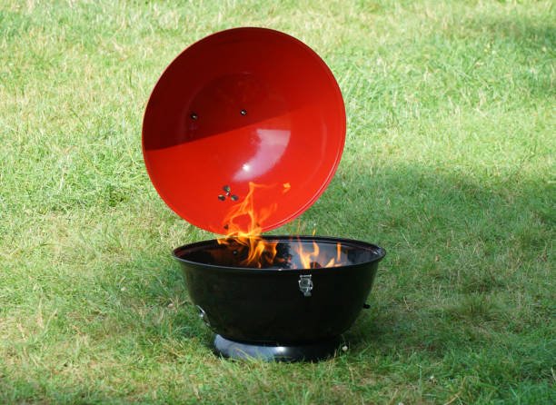 fire burning in charcoal kettle grill on the lawn